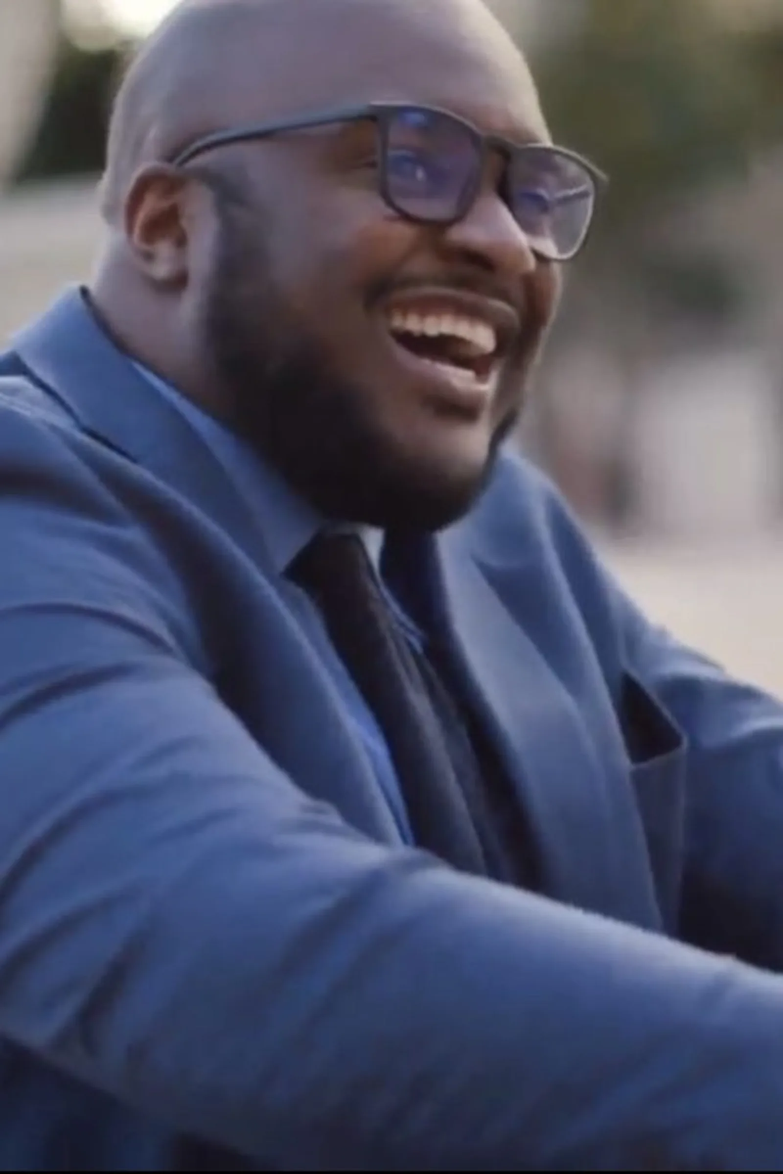 Dr. Alton Johnson laughing outdoors in a blue suit